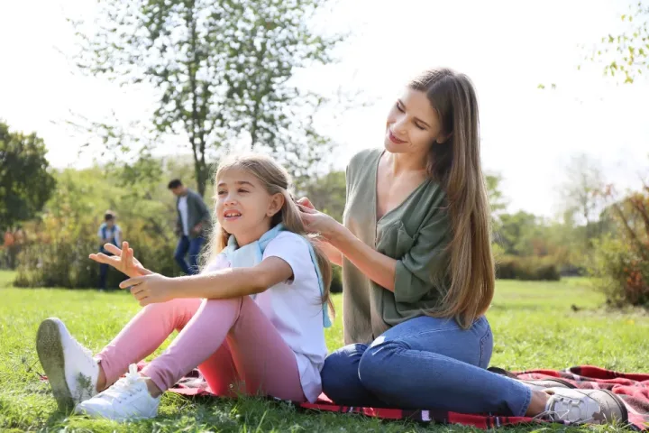 Parkta çimenlerde oturan anne ve kızı